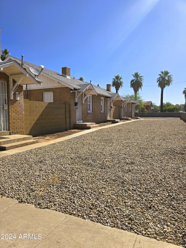 view of front of property featuring brick siding, fence, a garage, and driveway