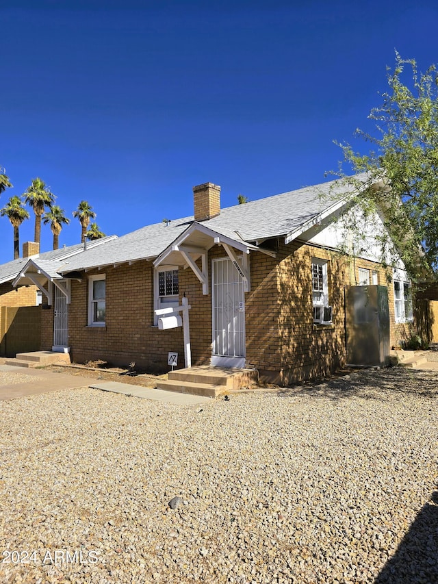 single story home with brick siding and a chimney