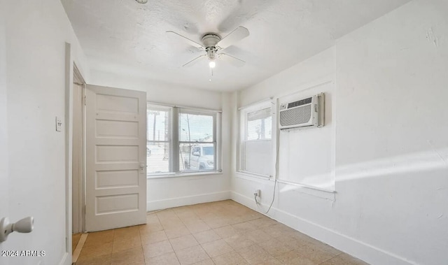 spare room featuring an AC wall unit, baseboards, and ceiling fan