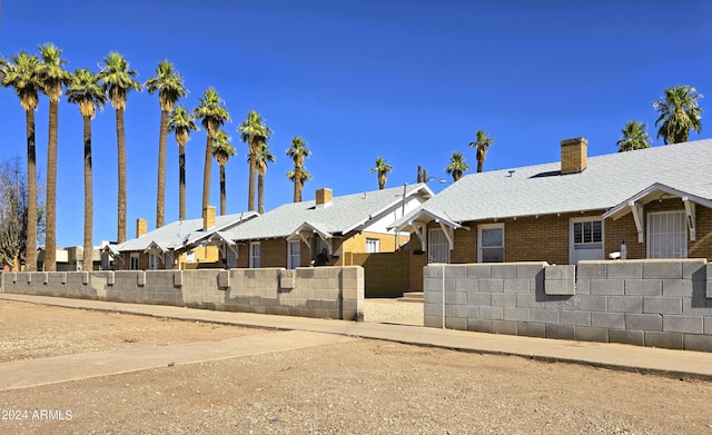 view of front facade with a fenced front yard, a residential view, a shingled roof, and brick siding