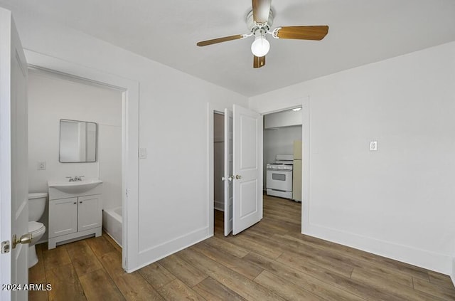 unfurnished bedroom with a sink, baseboards, and wood finished floors