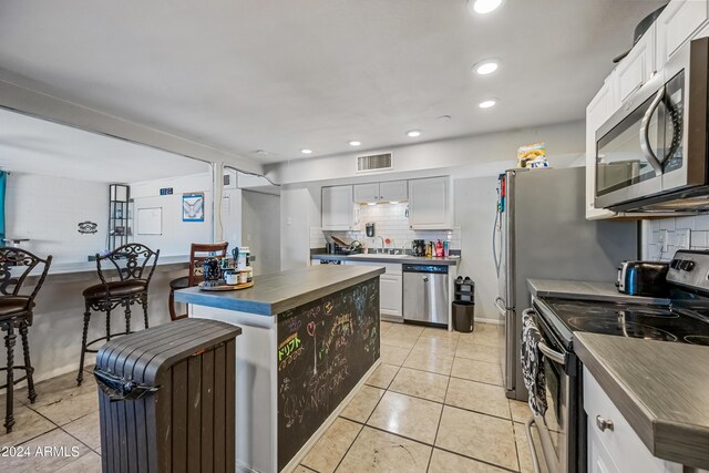 kitchen with backsplash, sink, light tile patterned flooring, white cabinetry, and stainless steel appliances