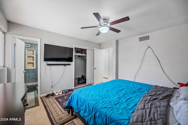 bedroom with ensuite bath, ceiling fan, a closet, and a textured ceiling