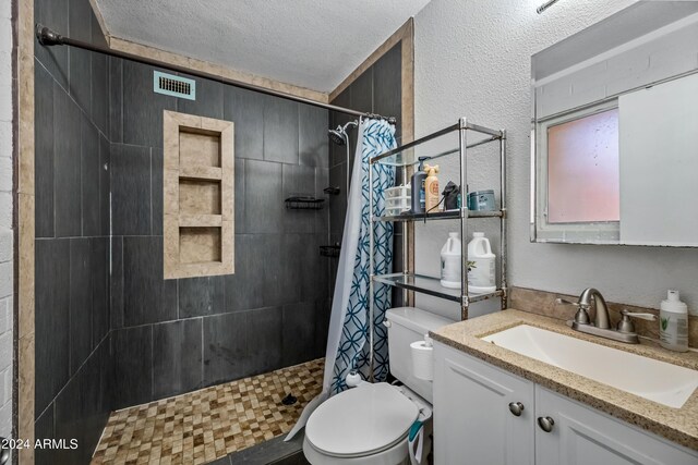 bathroom featuring vanity, curtained shower, toilet, and a textured ceiling