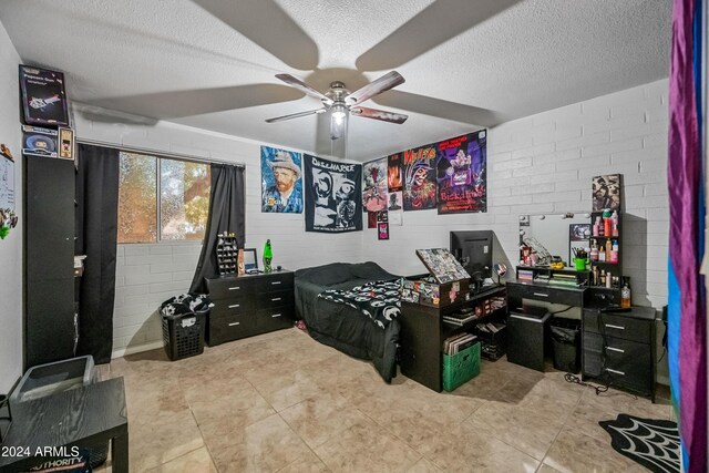 bedroom with ceiling fan, brick wall, and a textured ceiling