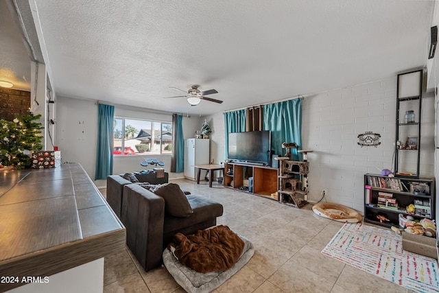 tiled living room with ceiling fan, brick wall, and a textured ceiling