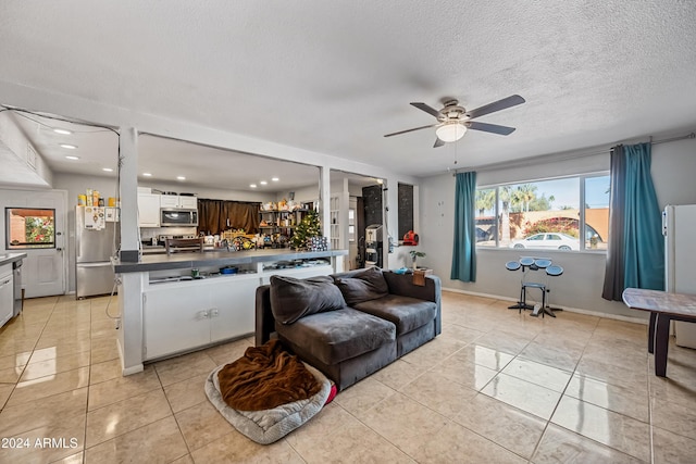 tiled living room with ceiling fan and a textured ceiling