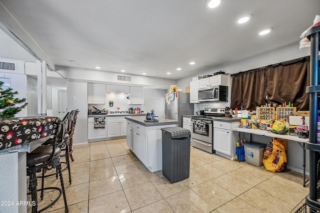 kitchen featuring stainless steel appliances, white cabinetry, tasteful backsplash, and a kitchen island