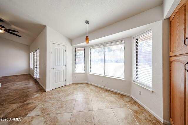 unfurnished dining area featuring plenty of natural light, baseboards, and vaulted ceiling