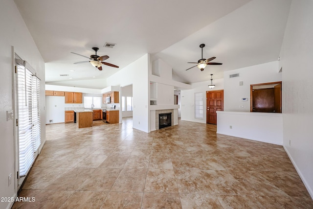 unfurnished living room featuring visible vents, ceiling fan, and a tiled fireplace
