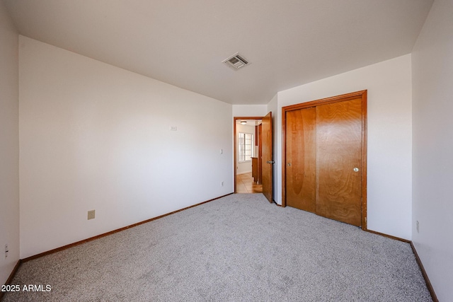 unfurnished bedroom featuring carpet flooring, baseboards, visible vents, and a closet