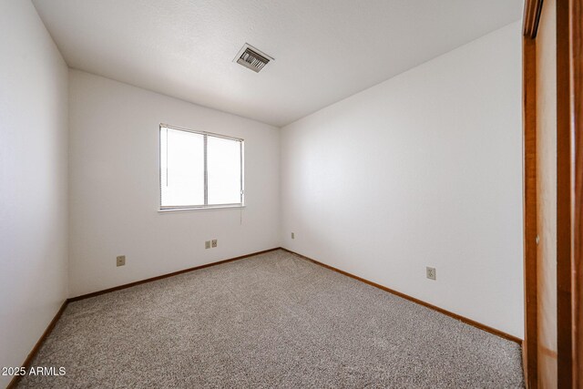 empty room featuring visible vents, light colored carpet, and baseboards