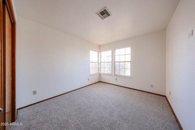 carpeted empty room featuring visible vents and baseboards