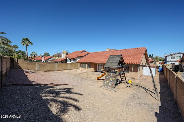 rear view of property with a tiled roof, a fenced backyard, and a residential view