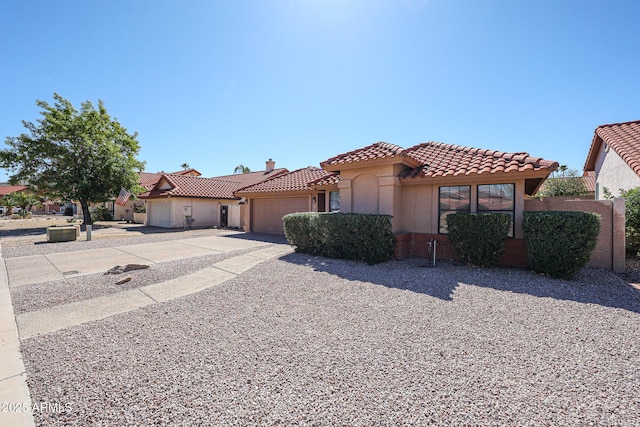 mediterranean / spanish-style home with concrete driveway, a tiled roof, a garage, and stucco siding