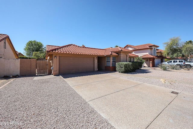 mediterranean / spanish home featuring a gate, driveway, an attached garage, stucco siding, and a tiled roof