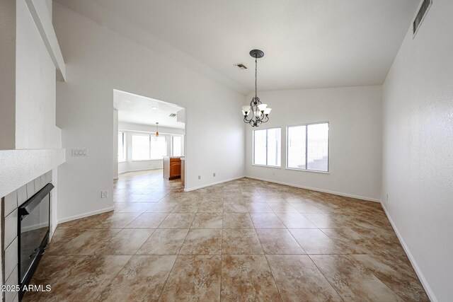 unfurnished dining area with a chandelier, visible vents, a tile fireplace, and baseboards