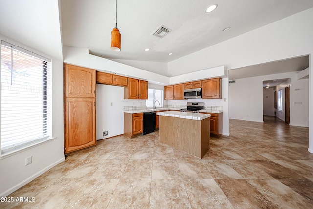 kitchen with visible vents, a kitchen island, tile countertops, stainless steel appliances, and vaulted ceiling