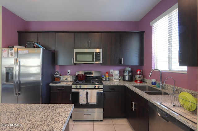 17743 N Rosa Dr, Maricopa, AZ 85138 - kitchen featuring light tile patterned floors, stainless steel appliances, a sink, light stone countertops, and dark brown cabinets