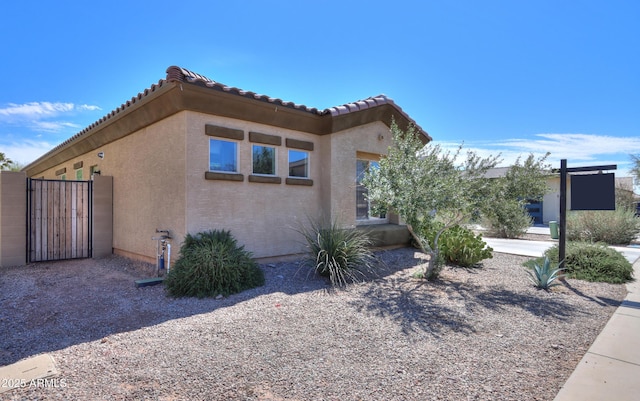 17743 N Rosa Dr, Maricopa, AZ 85138 - view of side of property featuring stucco siding, a gate, and a tile roof