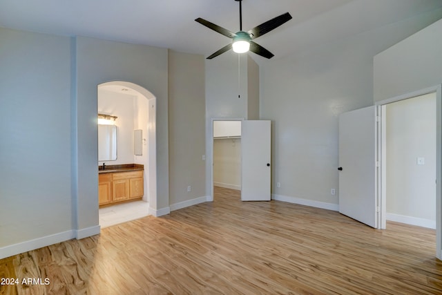 unfurnished bedroom featuring light hardwood / wood-style floors, sink, ensuite bath, a spacious closet, and ceiling fan