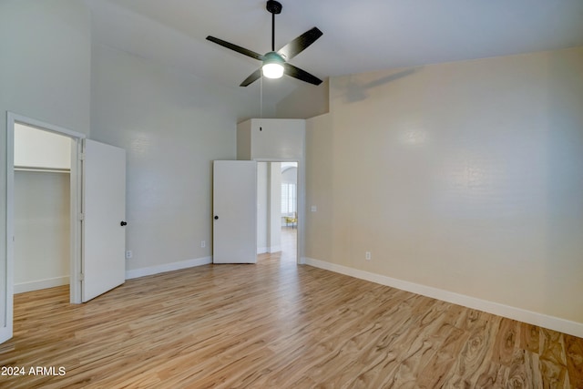 unfurnished bedroom with ceiling fan, high vaulted ceiling, a closet, a spacious closet, and light hardwood / wood-style floors