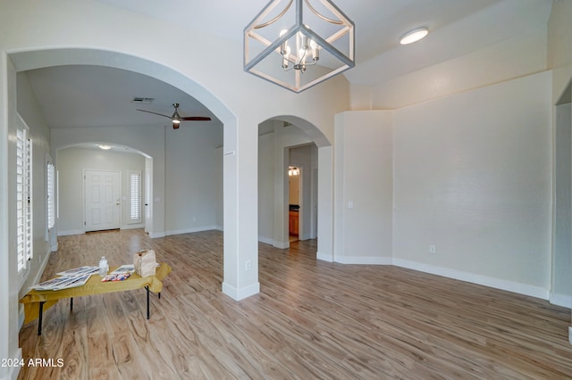 living room featuring ceiling fan with notable chandelier, light hardwood / wood-style flooring, and lofted ceiling