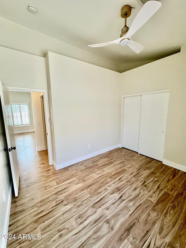 unfurnished bedroom featuring light hardwood / wood-style floors, ceiling fan, and a closet