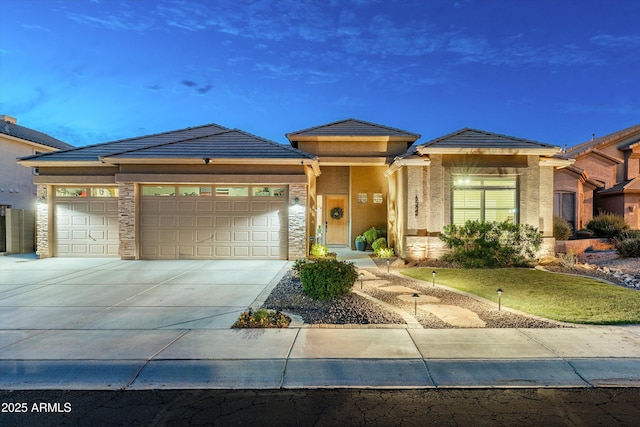 6326 W Misty Willow Ln, Glendale, AZ 85310 - prairie-style home with a garage, concrete driveway, stone siding, a front yard, and a tiled roof