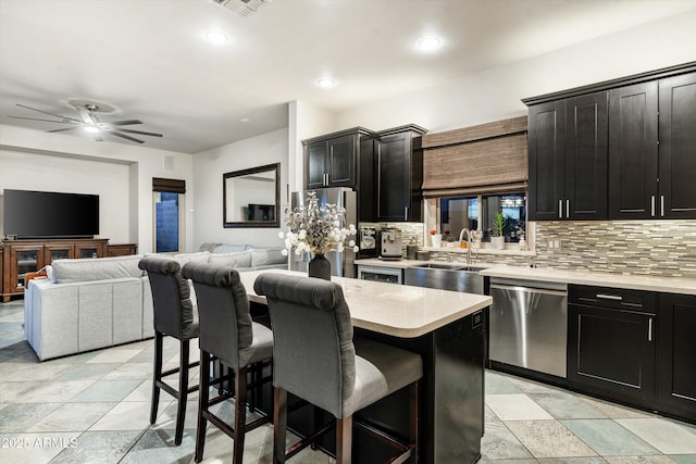 6326 W Misty Willow Ln, Glendale, AZ 85310 - kitchen with stainless steel appliances, a sink, a breakfast bar area, decorative backsplash, and dark cabinets