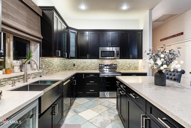 6326 W Misty Willow Ln, Glendale, AZ 85310 - kitchen with appliances with stainless steel finishes, dark cabinetry, a sink, backsplash, and wine cooler