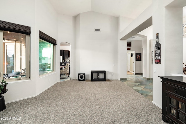 6326 W Misty Willow Ln, Glendale, AZ 85310 - unfurnished living room featuring arched walkways, high vaulted ceiling, carpet floors, and baseboards