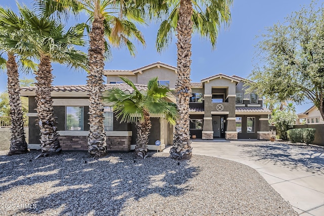 view of front facade with stucco siding, driveway, a tile roof, and a carport