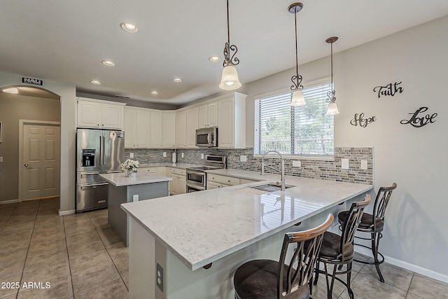 kitchen featuring a sink, appliances with stainless steel finishes, a center island, and backsplash