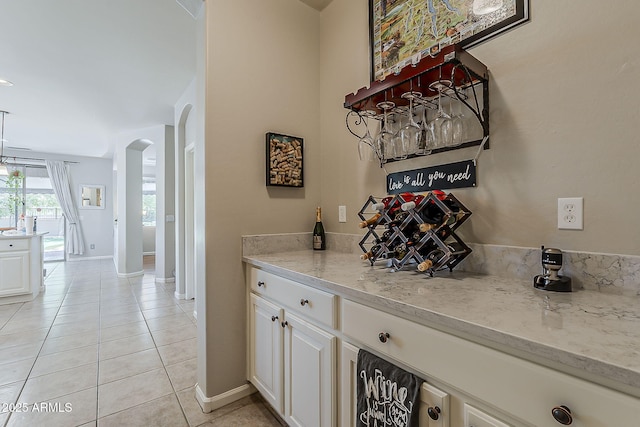 bar with arched walkways, baseboards, and light tile patterned flooring