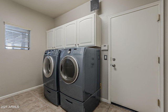 clothes washing area featuring baseboards, cabinet space, light tile patterned floors, and washing machine and clothes dryer