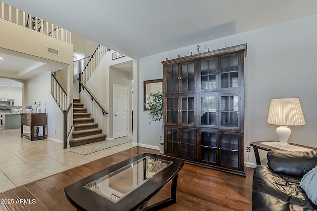 living area with stairs, baseboards, visible vents, and wood finished floors