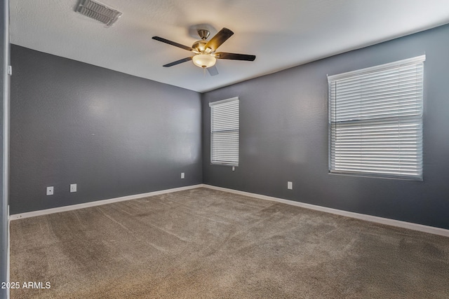 unfurnished room featuring a wealth of natural light, carpet floors, and ceiling fan