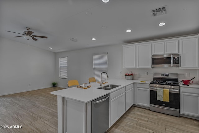 kitchen with stainless steel appliances, sink, white cabinets, and kitchen peninsula