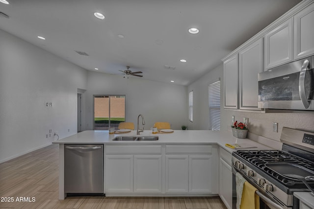 kitchen featuring sink, kitchen peninsula, a wealth of natural light, stainless steel appliances, and white cabinets