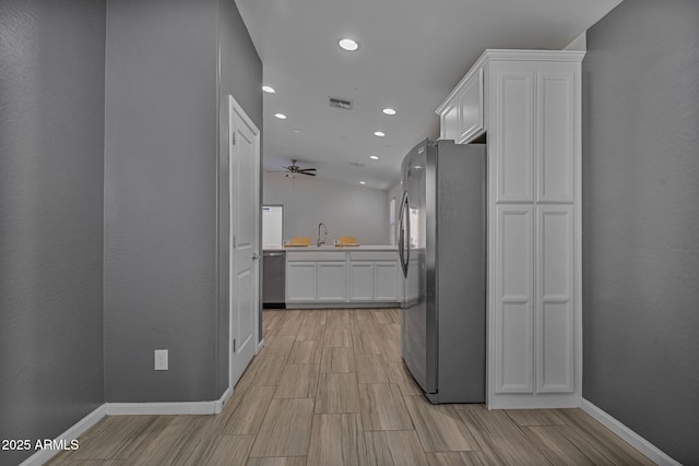 kitchen featuring lofted ceiling, sink, stainless steel appliances, and white cabinets