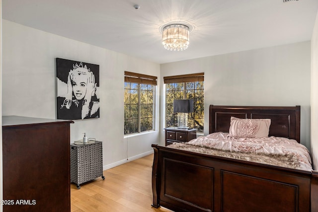 bedroom with a chandelier, light wood-style flooring, and baseboards