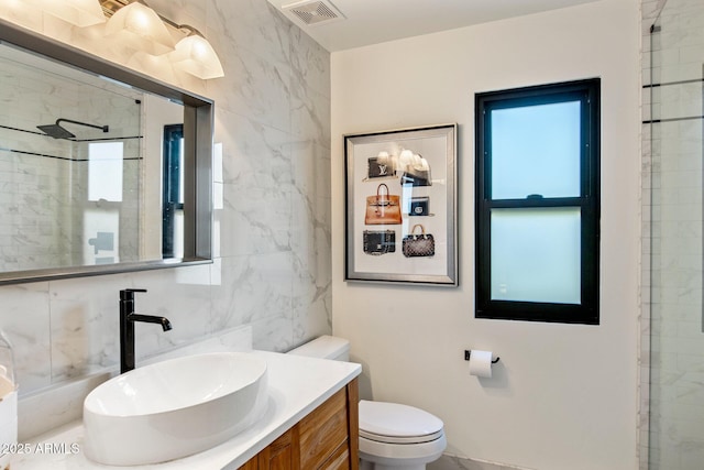 bathroom with visible vents, toilet, an enclosed shower, vanity, and tile walls