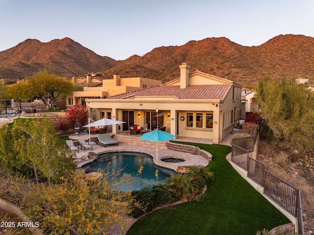 rear view of house with a fenced backyard, a mountain view, a tiled roof, and stucco siding