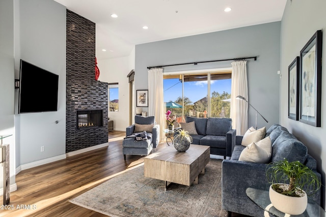 living room with baseboards, dark wood-type flooring, a fireplace, and recessed lighting