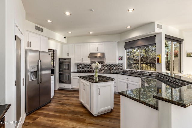 kitchen with stainless steel fridge with ice dispenser, a center island, multiple ovens, under cabinet range hood, and white cabinetry