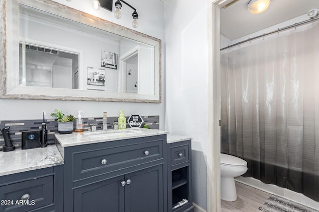 full bathroom featuring wood-type flooring, shower / tub combo with curtain, vanity, and toilet