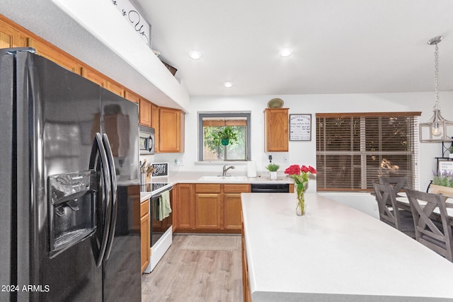 kitchen with sink, light hardwood / wood-style flooring, hanging light fixtures, a center island, and black appliances