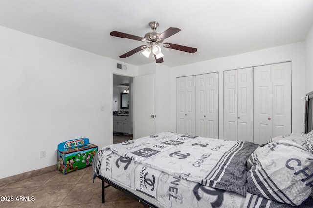 bedroom with ceiling fan, sink, tile patterned flooring, and two closets