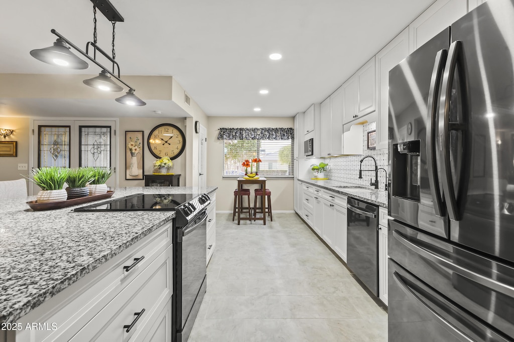 kitchen with decorative backsplash, stainless steel appliances, sink, pendant lighting, and white cabinetry